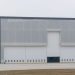 Front view of a large modern warehouse with closed doors, showcasing industrial architecture