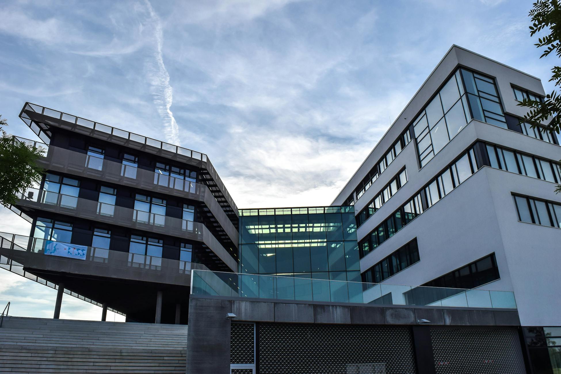 A modern glass-facade building against a blue sky, featuring innovative architecture.