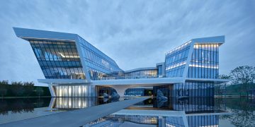 Modern architectural marvel with reflective glass panels by a water body during daytime.