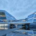 Modern architectural marvel with reflective glass panels by a water body during daytime.