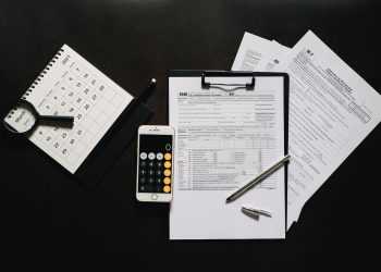 Flat lay of financial tools for tax preparation including forms, calculator, and calendar.