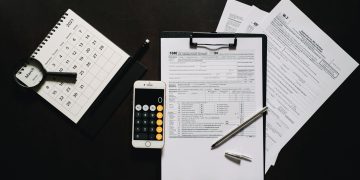 Flat lay of financial tools for tax preparation including forms, calculator, and calendar.