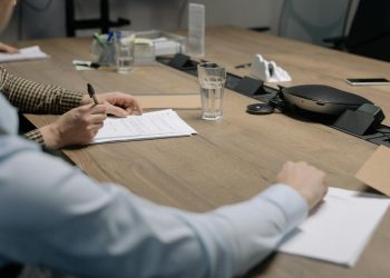Professional setting of a business meeting with individuals signing documents on a conference table.