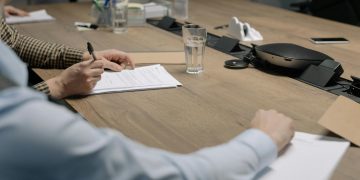 Professional setting of a business meeting with individuals signing documents on a conference table.