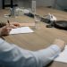 Professional setting of a business meeting with individuals signing documents on a conference table.