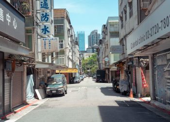 A typical street scene in Taipei, featuring local shops and a view of city buildings.