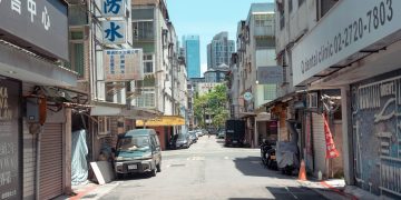 A typical street scene in Taipei, featuring local shops and a view of city buildings.