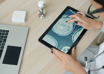 Doctor examining brain scan on tablet at desk.