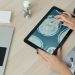 Doctor examining brain scan on tablet at desk.