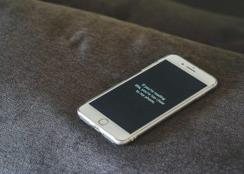 A smartphone with a humorous lock screen message placed on a grey couch, emphasizing privacy.