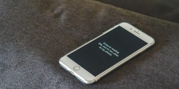 A smartphone with a humorous lock screen message placed on a grey couch, emphasizing privacy.