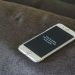 A smartphone with a humorous lock screen message placed on a grey couch, emphasizing privacy.