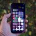 Hand holding a smartphone with colorful app icons.