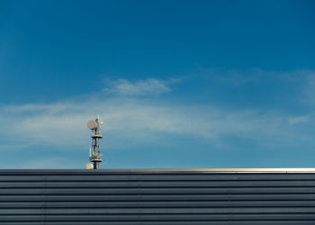 A modern telecommunication tower stands against a clear blue sky, showcasing technological advancement.