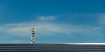 A modern telecommunication tower stands against a clear blue sky, showcasing technological advancement.