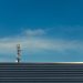 A modern telecommunication tower stands against a clear blue sky, showcasing technological advancement.