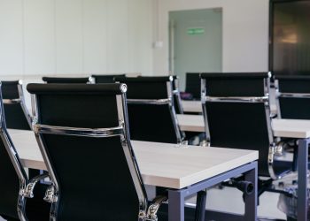 Sleek modern conference room with black chairs and white desks, suitable for business meetings.