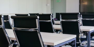 Sleek modern conference room with black chairs and white desks, suitable for business meetings.