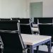 Sleek modern conference room with black chairs and white desks, suitable for business meetings.