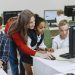Teacher engaging with diverse children in a technology lesson using computers in a modern classroom.