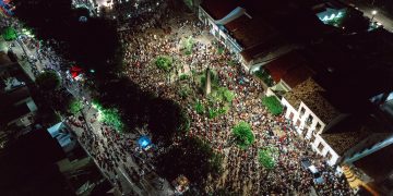 A lively aerial view of a crowded nighttime street festival with illuminated streets.