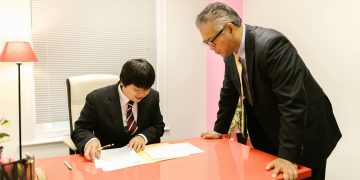 Two businessmen discussing paperwork in a modern office environment.