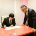 Two businessmen discussing paperwork in a modern office environment.