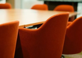 Close-up view of modern orange chairs around a conference table in an office setting.