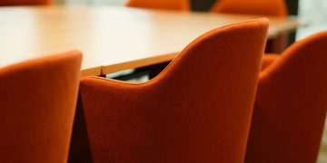 Close-up view of modern orange chairs around a conference table in an office setting.