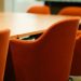 Close-up view of modern orange chairs around a conference table in an office setting.
