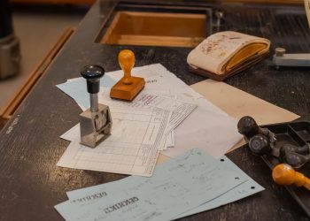 Cluttered desk with office stamps on top of various documents in an office setting.