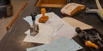 Cluttered desk with office stamps on top of various documents in an office setting.