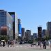 Vibrant street scene in Seoul with skyscrapers and people crossing under a clear blue sky.