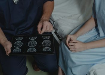 A doctor shows and explains brain scan images to a patient in a medical setting.
