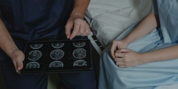 A doctor shows and explains brain scan images to a patient in a medical setting.