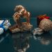 High angle composition of Ox year symbol figurine and wrapped presents placed on mirrored table with coins and rolled and tied dollar banknotes