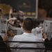 A candid moment of people reading newspapers on a bench in Ankara park.