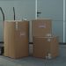 Three cardboard boxes on a dolly, ready for shipping outside a warehouse.