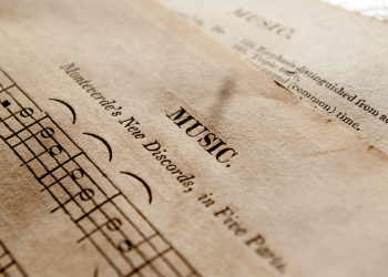 Detailed view of antique music sheets featuring notes and Monteverde's New Discords in sepia tone.