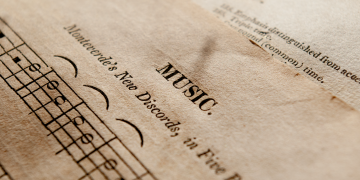 Detailed view of antique music sheets featuring notes and Monteverde's New Discords in sepia tone.