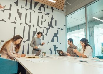 Group of colleagues engaged in a brainstorming session in a contemporary office with abstract design.