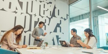 Group of colleagues engaged in a brainstorming session in a contemporary office with abstract design.