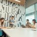 Group of colleagues engaged in a brainstorming session in a contemporary office with abstract design.