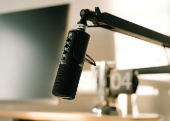 A studio microphone on a boom arm in soft, warm lighting, perfect for podcasts or voiceovers.
