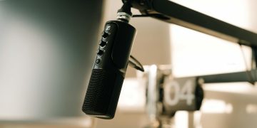 A studio microphone on a boom arm in soft, warm lighting, perfect for podcasts or voiceovers.