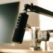 A studio microphone on a boom arm in soft, warm lighting, perfect for podcasts or voiceovers.