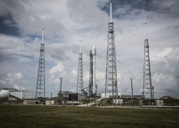 Industrial rocket launch pad with tall towers under a cloudy sky, perfect for technology and energy themes.