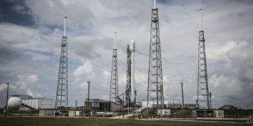 Industrial rocket launch pad with tall towers under a cloudy sky, perfect for technology and energy themes.