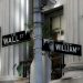 Intersection of Wall Street and William Street, showcasing iconic financial district signage in New York City.