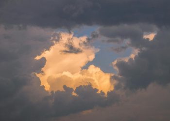 A captivating cloudscape featuring golden clouds illuminated by the setting sun, creating a serene and ethereal atmosphe